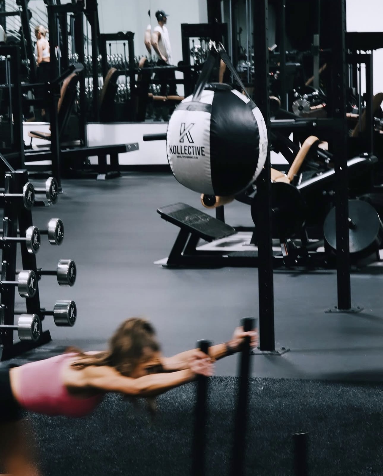 Kollective-branded performance floor with dumbbells and a signature K medicine ball