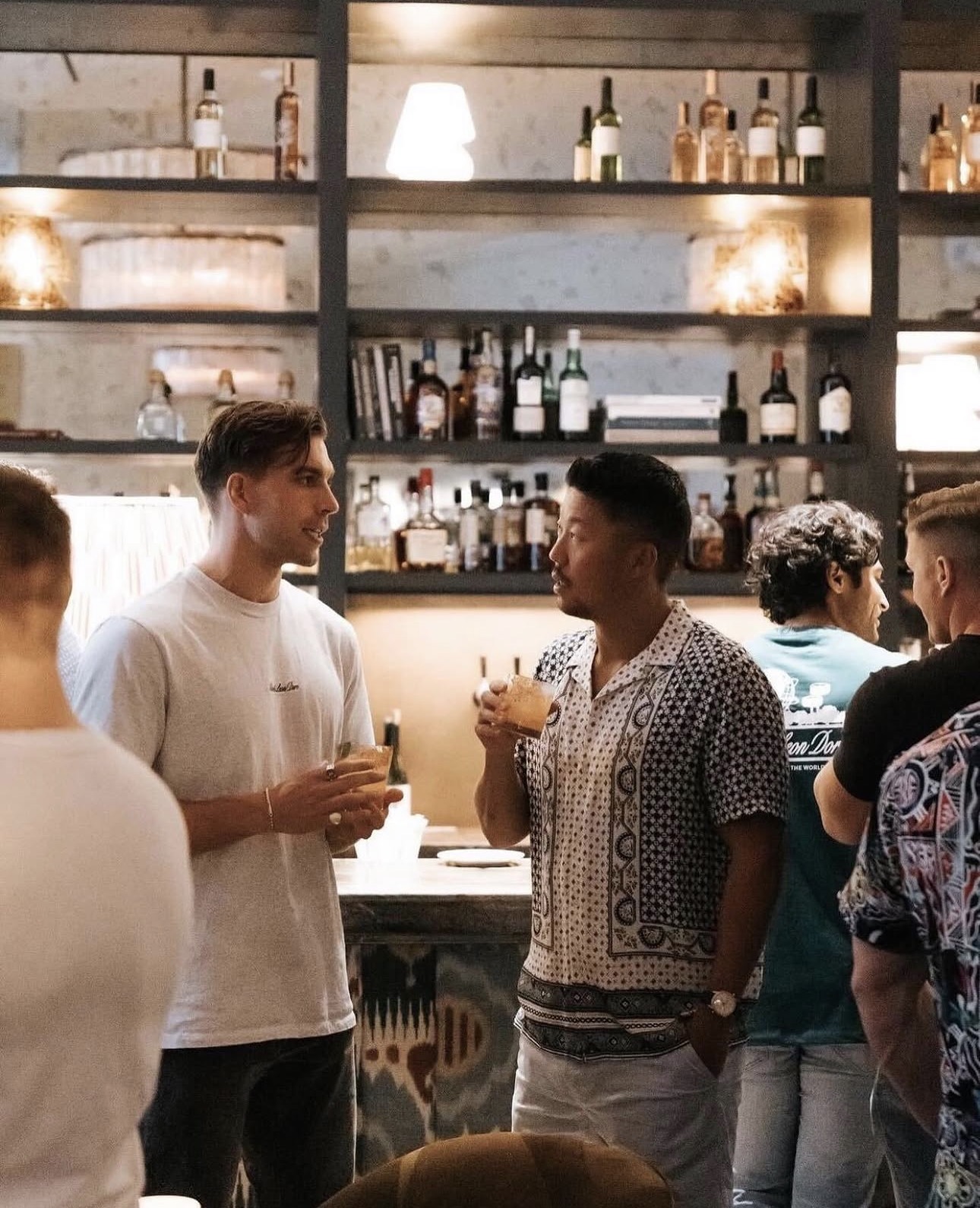 Two members in candid conversation over drinks at the club bar