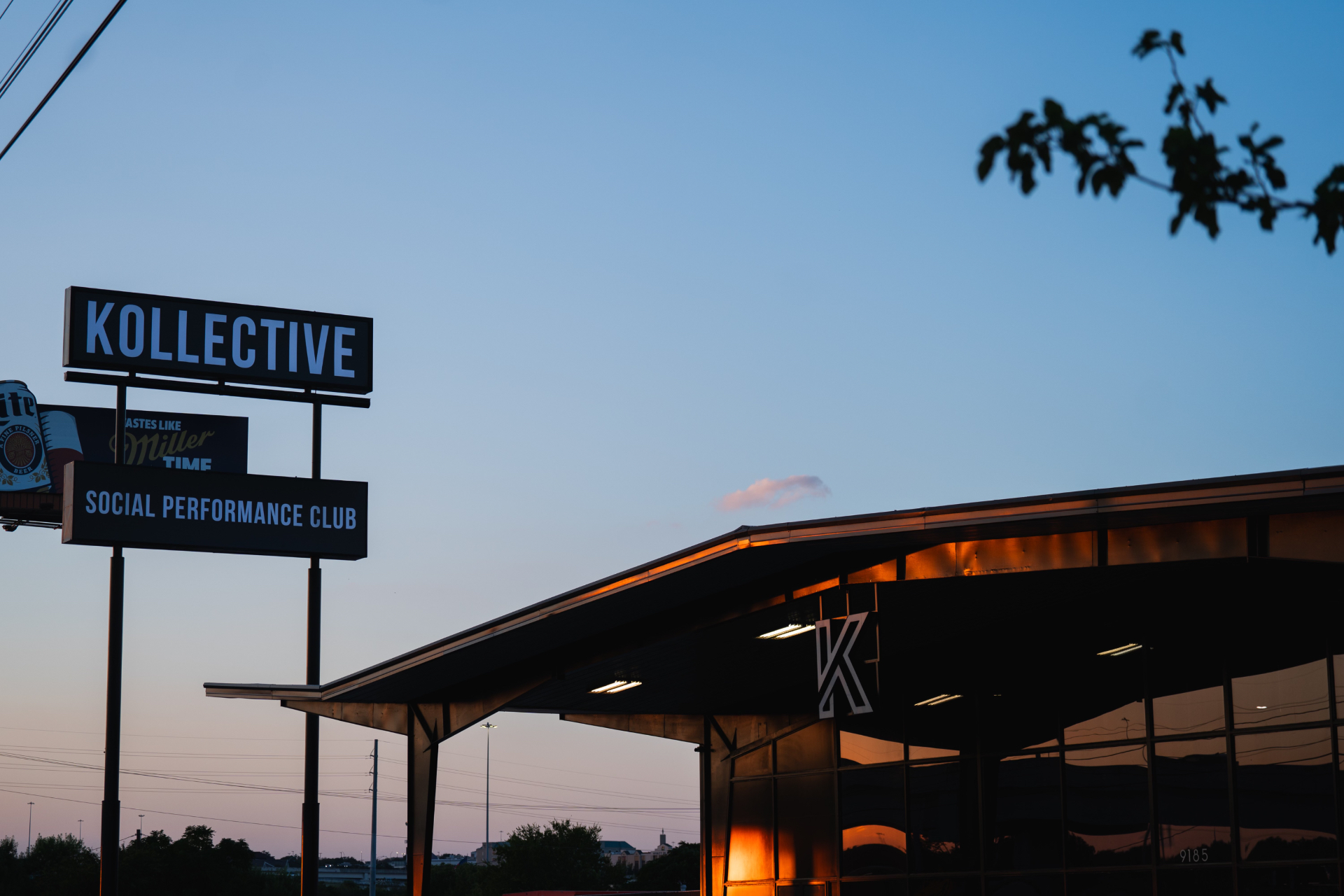 The Kollective Social Performance Club roadside signage at dusk