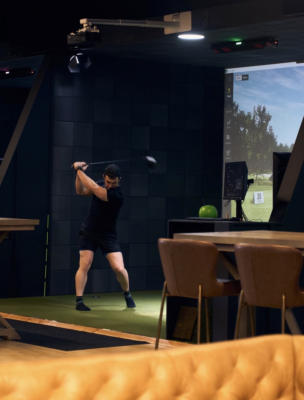 Member hitting a driver in the golf simulator bay