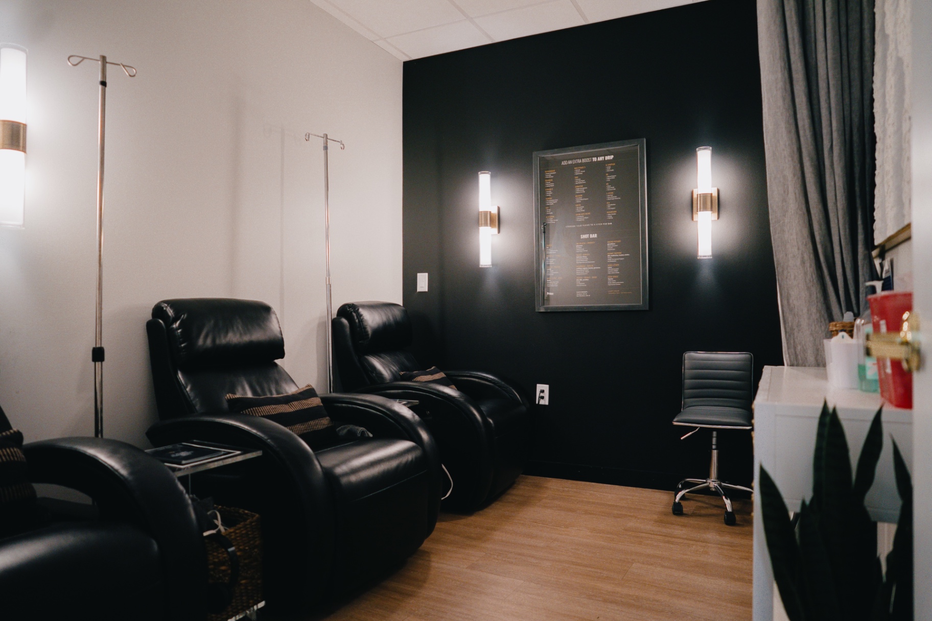 IV therapy suite with black leather recliners and warm sconce lighting